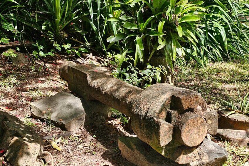 A large, weathered concrete structure with a cylindrical shape and a flat top, surrounded by greenery and rocks. 3