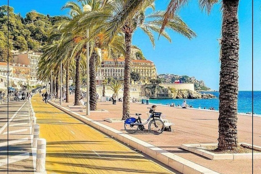 Een kustpromenade met palmbomen, een fiets en een scooter geparkeerd op het trottoir. 4