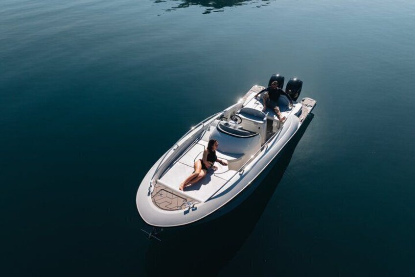 A white motorboat with two people on board, floating on calm water. 4