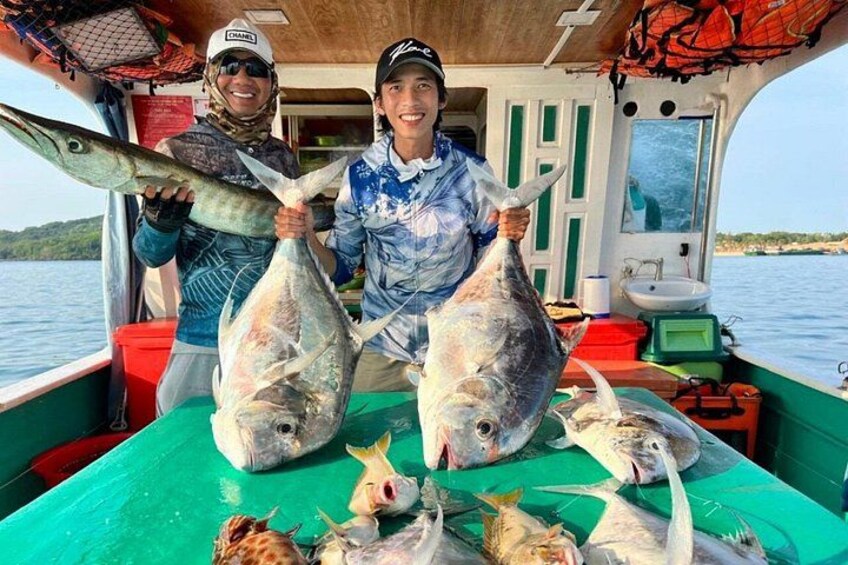 Due persone che tengono in mano pesci grandi su una barca, con un tavolo pieno di pesce e attrezzatura da pesca. 5