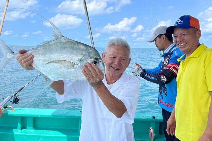 Una persona tiene in mano un pesce grande, una barca e l'oceano. 3