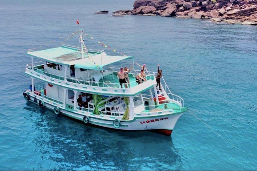 Una barca con persone a bordo che galleggia su acqua cristallina e blu. 1