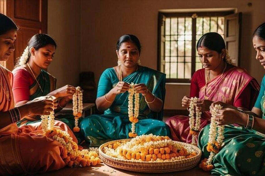 A group of women in traditional attire, sitting and arranging flowers. 1
