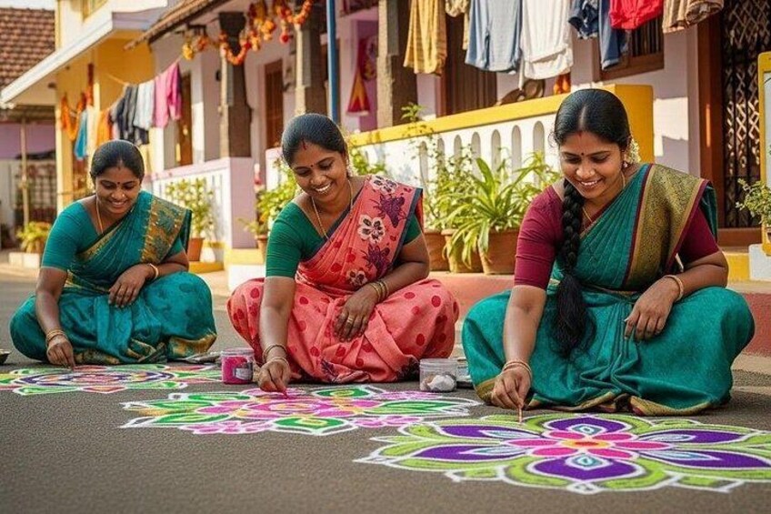 Three women in traditional attire creating colorful rangoli designs on the ground. 5
