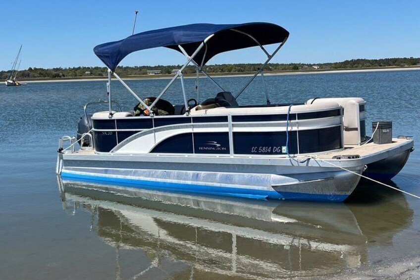 Un bote con toldo azul, número de registro SC 5814 DG, amarrado en aguas tranquilas bajo un cielo despejado. 2
