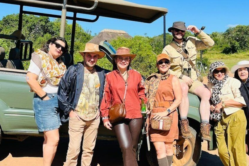 A group of people posing in front of a safari vehicle. 2