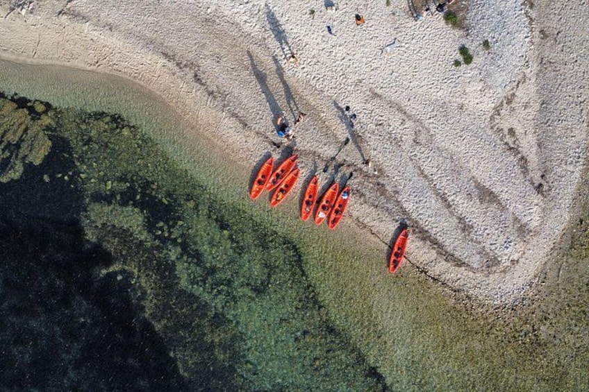 Des kayaks sont alignés sur une plage, avec une eau claire et une zone rocheuse. 2