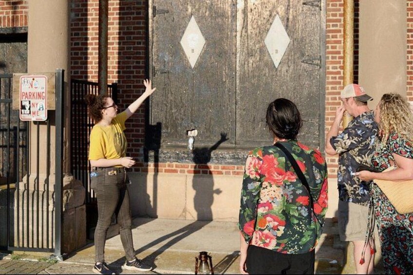 A person gesturing towards a building, a sign indicating no parking, and a group of people standing nearby. 3