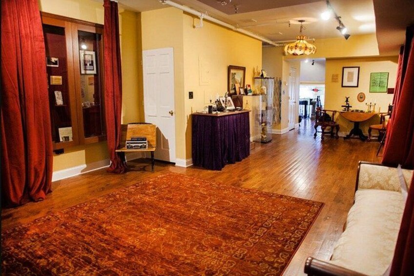 A room with a wooden floor, a large rug, a sofa, a table, and a chandelier. 2
