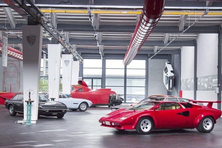Un concessionnaire automobile où sont exposés différents modèles de voitures de sport, notamment une voiture rouge décapotable et une voiture de sport blanche. 5