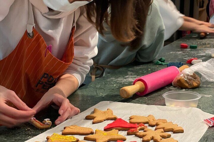 Personas decorando galletas de jengibre con glaseado y confites. 5