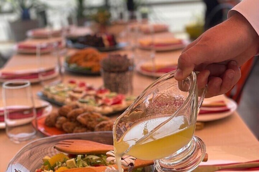 Una persona sirve un líquido amarillo de una jarrón sobre un plato de comida. 3