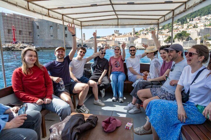 Eine Gruppe von Menschen auf einem Boot, im Hintergrund eine historische Stadtansicht. 5