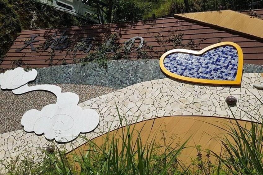 A decorative outdoor area with a heart-shaped mosaic, a cloud-shaped cutout, and a stone pathway. 3