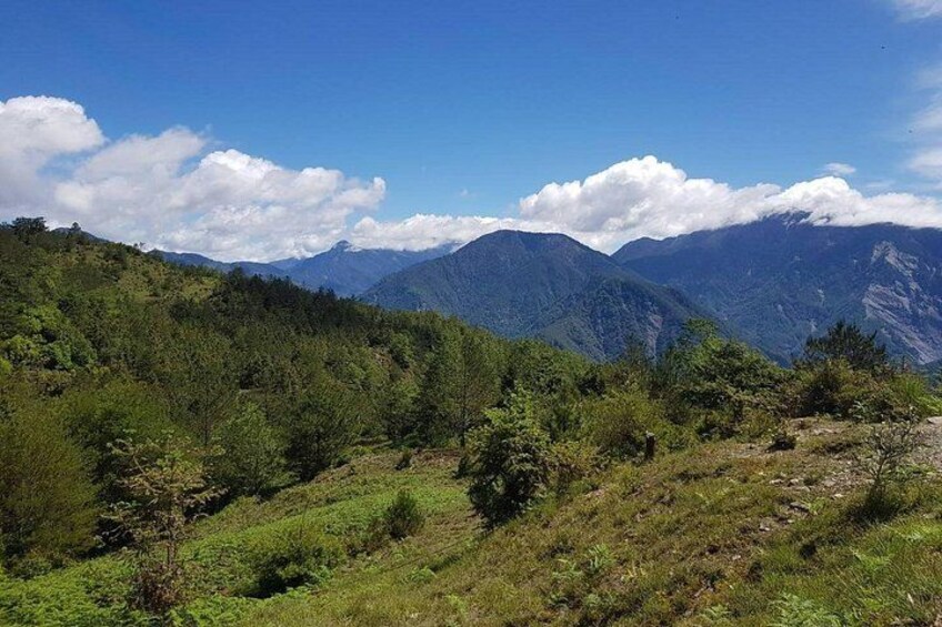 A mountainous landscape with dense green vegetation and a clear blue sky. 4