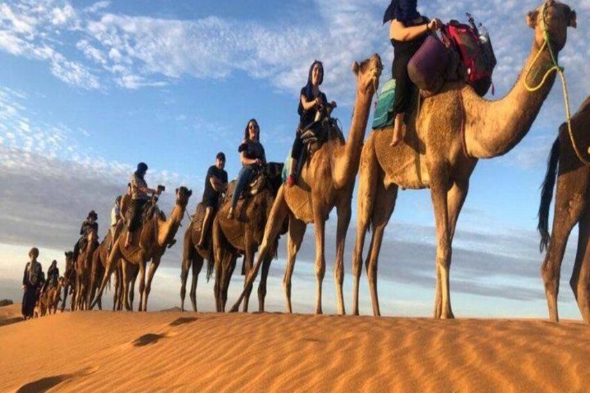 A group of people riding camels on a sandy terrain. 2