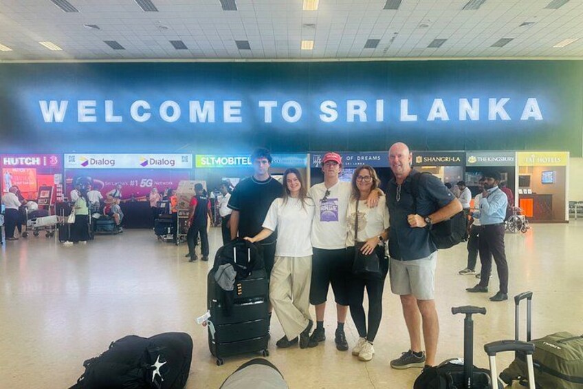 A group of people at an airport with a sign reading 'WELCOME TO SRI LANKA'. 5