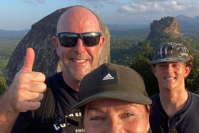 Three people in a mountainous landscape with a large rock formation in the background. 3