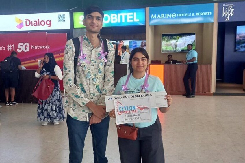 A man and a woman holding a welcome sign at a hotel reception. 2
