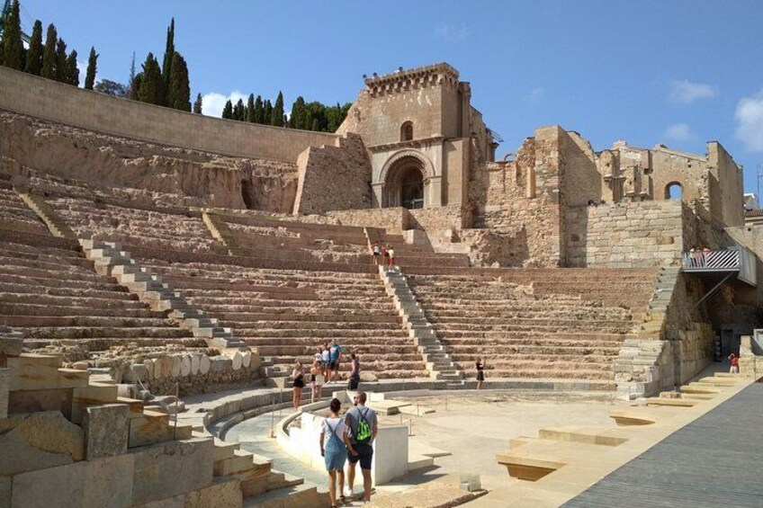 An ancient amphitheater with stone steps and ruins. 1