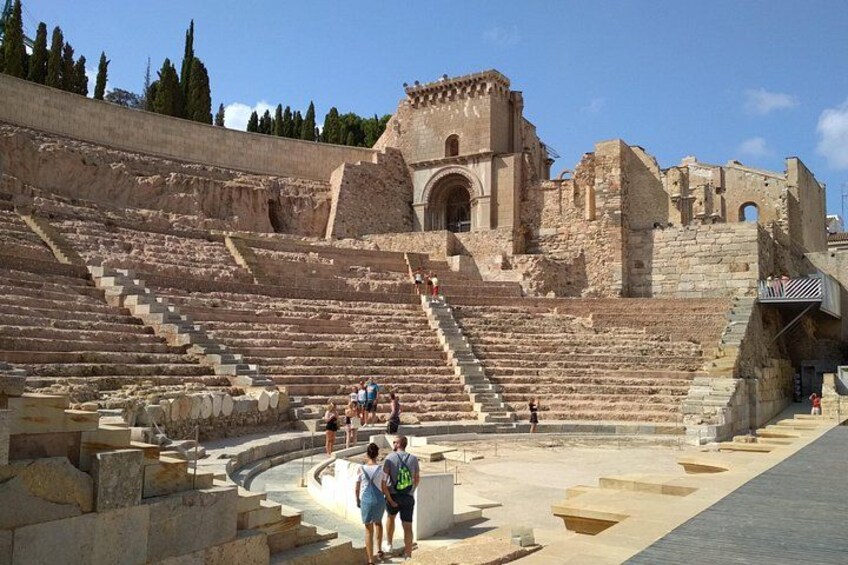 Un amphithéâtre antique avec des gradins en pierre et des ruines. 1