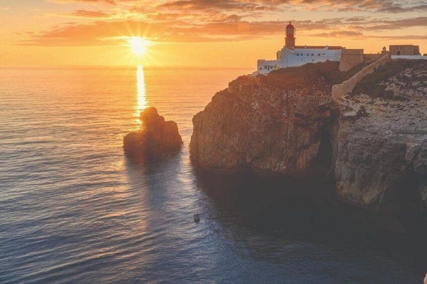 Ein Küsten-Sonnenuntergang mit einem Leuchtturm auf einer Klippe, ruhigem Meer und felsigem Gelände. 1