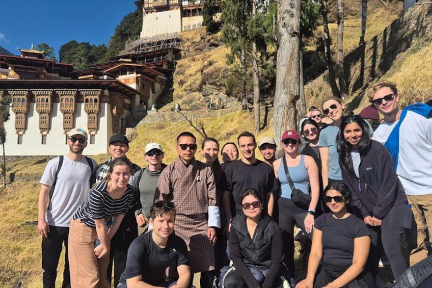 Un grupo de personas posando frente a un templo con montañas al fondo. 1