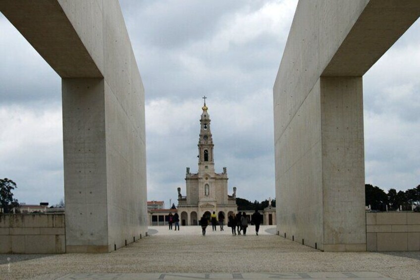 A large open plaza with a prominent church tower in the background, surrounded by concrete structures. 4