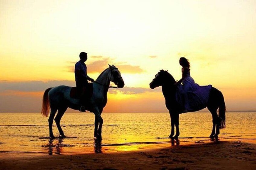 Deux personnes à cheval sur une plage au coucher du soleil. 4