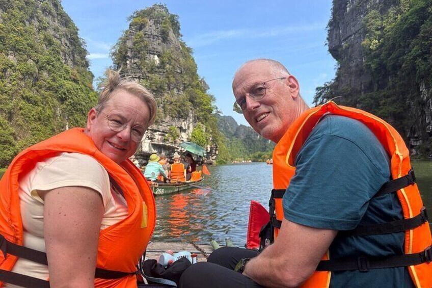 Deux personnes portant des gilets de sauvetage orange se trouvent sur un bateau dans une rivière, entourée de falaises. 3