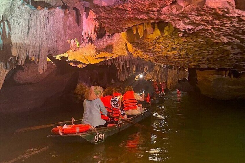 Des personnes se trouvent dans un bateau à l’intérieur d’une grotte, entourées de formations rocheuses aux couleurs vives. 2