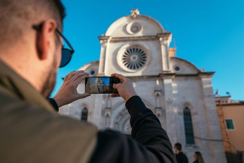 En person fotograferer en hvid kirke med en kuppel og et rundt vindue. 3