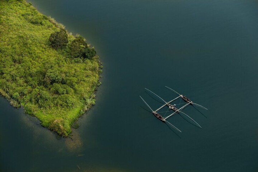Vue aérienne d’une petite île couverte d’une végétation luxuriante et verdoyante, avec un bateau traditionnel ancré près du rivage. 3