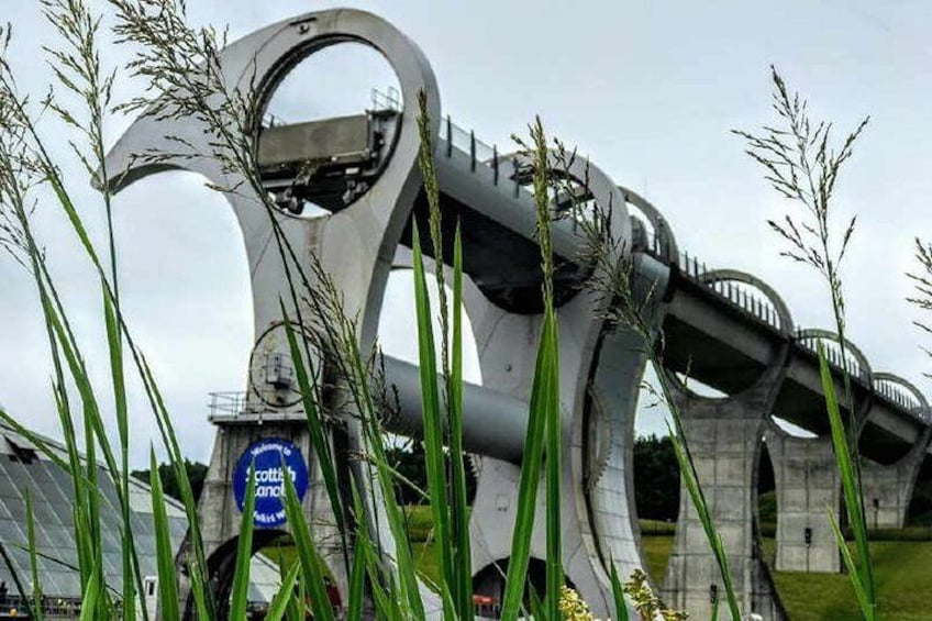 A modern bridge with a unique circular design, surrounded by tall grass and a sign that reads "cottage by the sea." 3