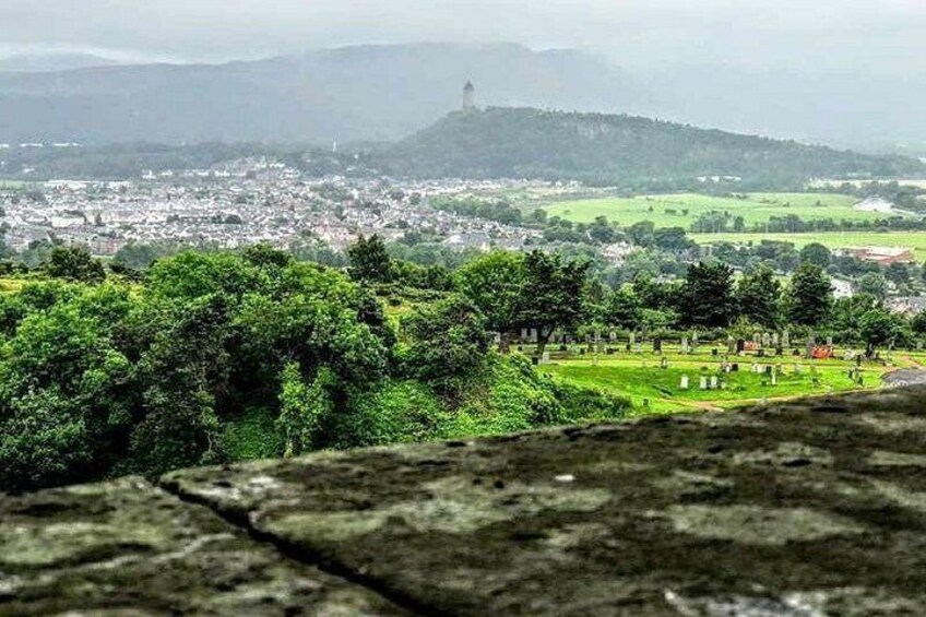 A landscape with a view of a town, green fields, and a hill with a tower. 2