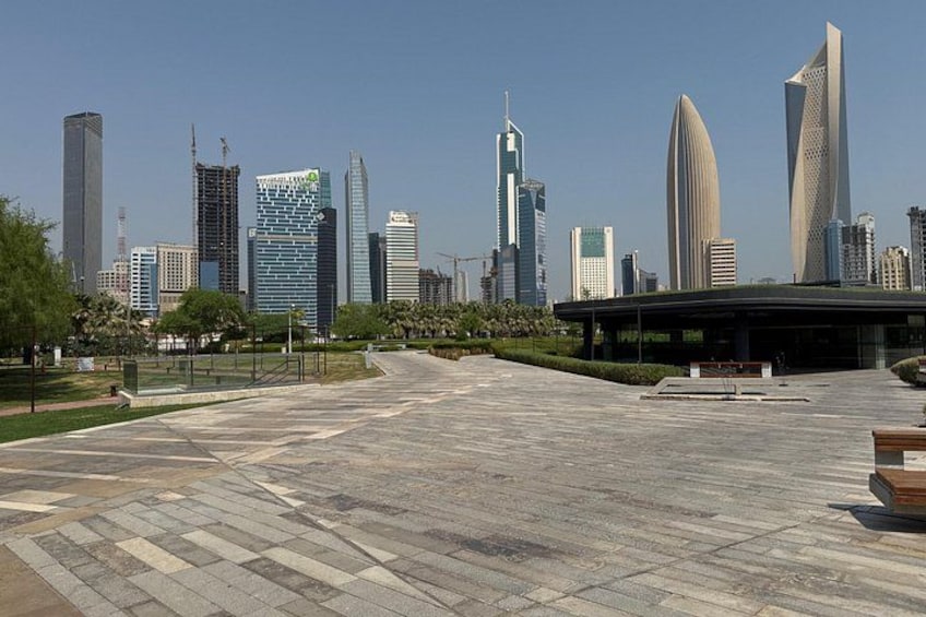 A cityscape with modern skyscrapers, a large open plaza, and a park area. 3