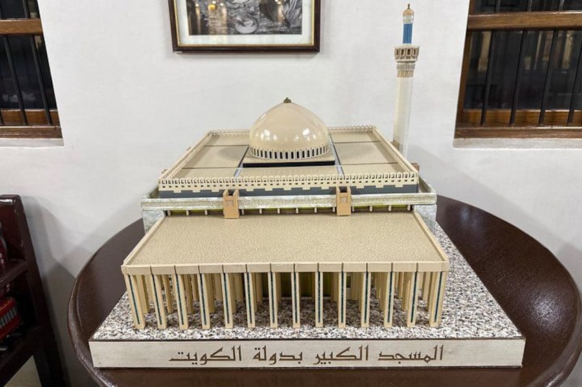 A model of a mosque with a dome and minaret, placed on a table with Arabic text. 5