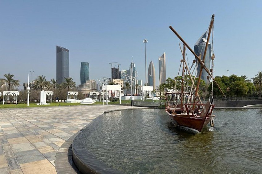 A waterfront with a sailboat, modern buildings, and a tiled walkway. 4