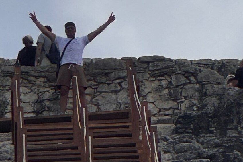 A person standing on a wooden staircase with arms outstretched, overlooking a rocky landscape. 1
