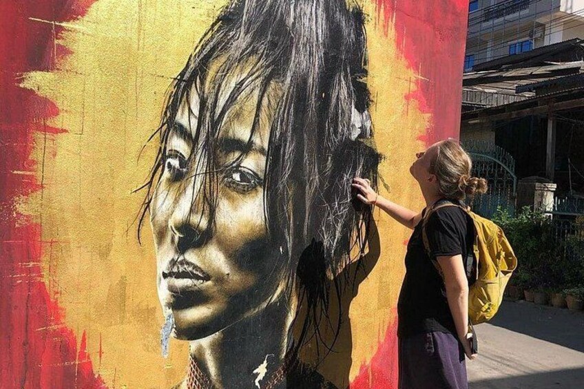 A mural of a person on a wall with a yellow backpack. 1