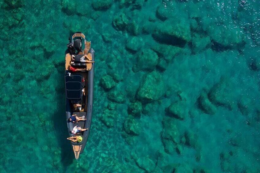 An aerial view of a small boat with people on a clear turquoise sea. 1