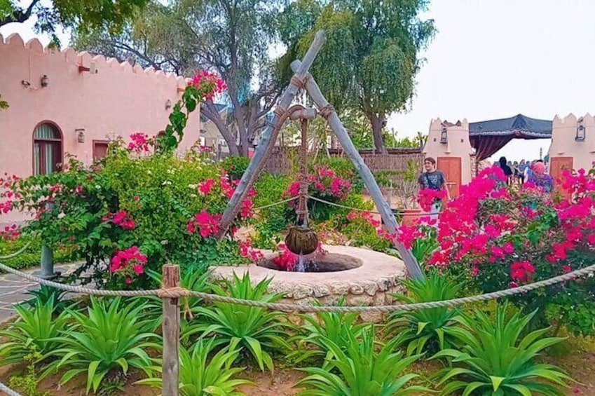 Un jardin avec une fontaine, des bougainvilliers roses et un bâtiment de couleur rose. 3