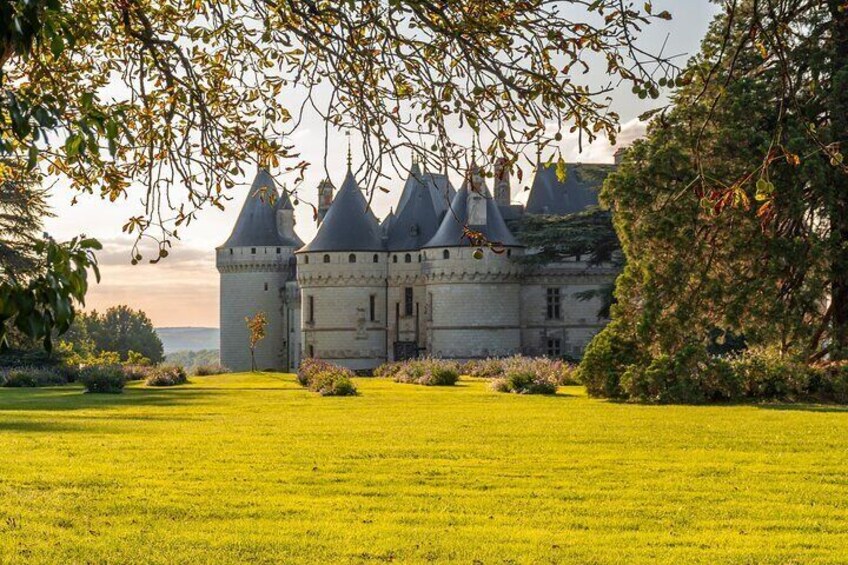 A castle with multiple towers, surrounded by a well-maintained lawn and trees. 3