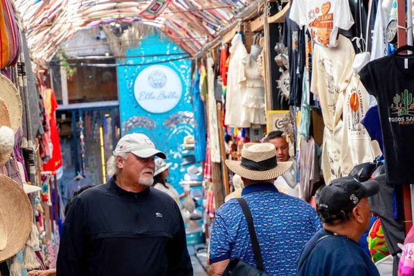 A crowded market with various stalls selling textiles and hats. 2