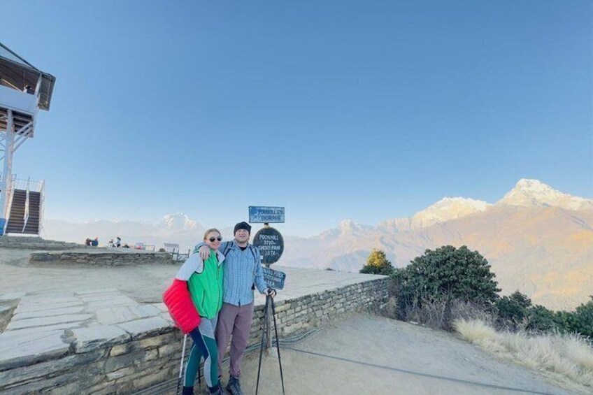 Un couple se tient près d’un panneau indicateur, avec une chaîne de montagnes en arrière-plan. 5