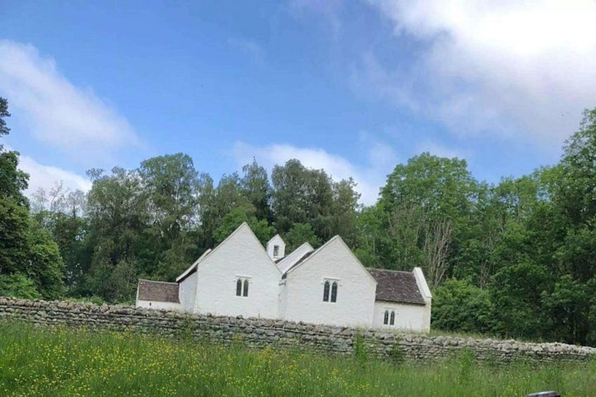 Ein weißes Haus mit Satteldach, umgeben von Grünpflanzen und einer Steinmauer. 4