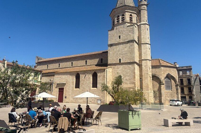 A historic church with a bell tower, outdoor seating area with umbrellas, and a clear blue sky. 5