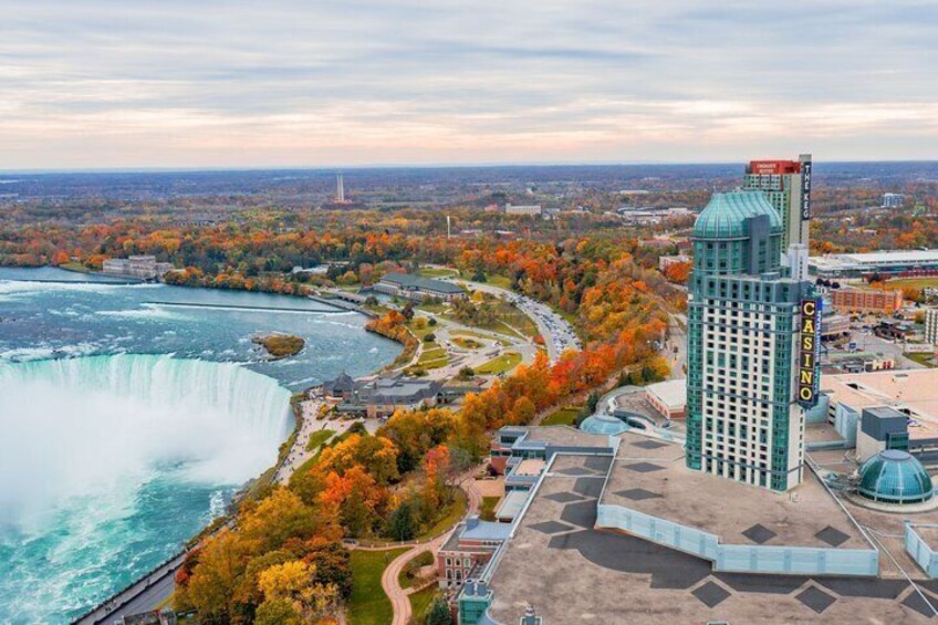 Vista de las Cataratas del Niágara, un imponente edificio de casino y árboles de colores otoñales. 2
