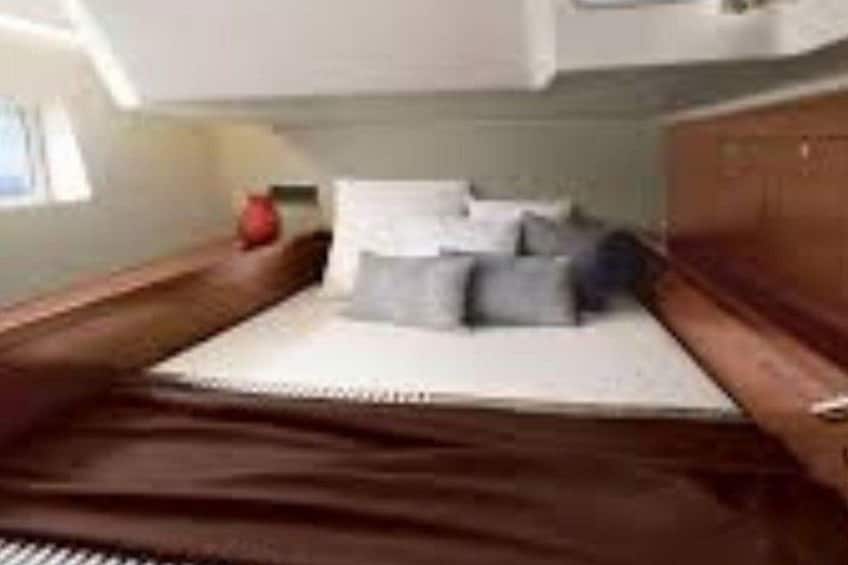 Una cama con colchón blanco, almohadas y un objeto rojo al lado. 3