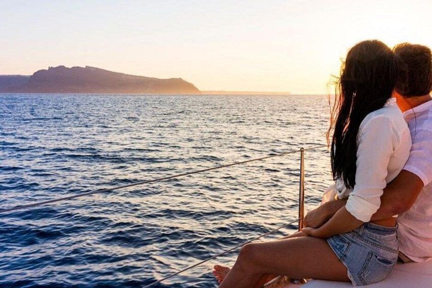 Una pareja sentada en un bote, mirando al mar con una masa de tierra distante al fondo. 2